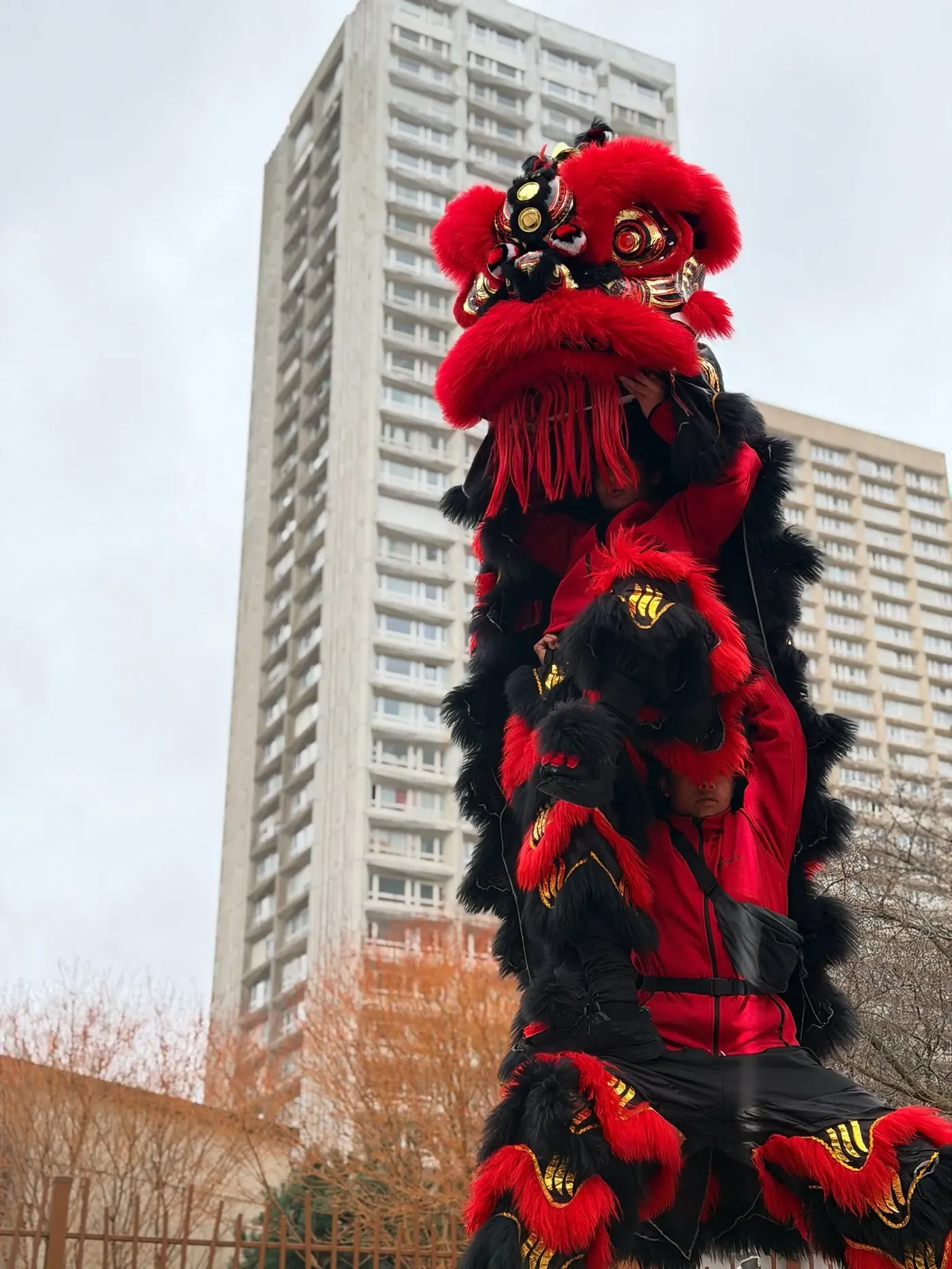 Lion rouge porté en hauteur — acrobatie Nouvel An chinois Paris
